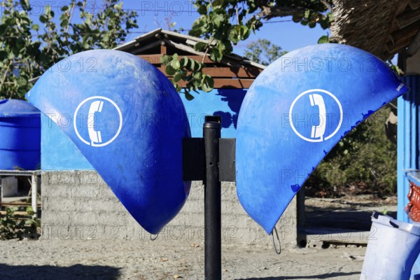 Baracoa, Cuba, Central America, Two blue public telephone boxes under bright sunshine, in front of