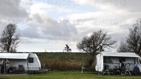 Caravan and motorhome on a campsite, a cyclist drives across the dike on the Baltic Sea, Fehmarn,