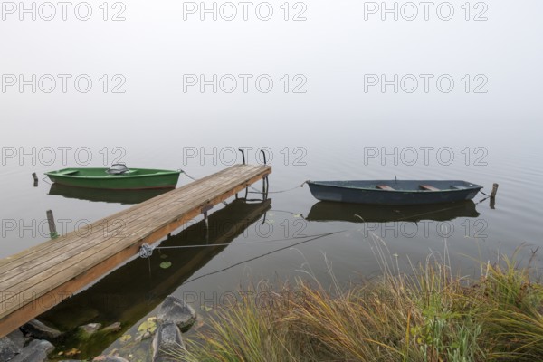 Two boats next to a dock in foggy, quiet surroundings, Hopfensee, Ostallgäu, Bavaria, Germany