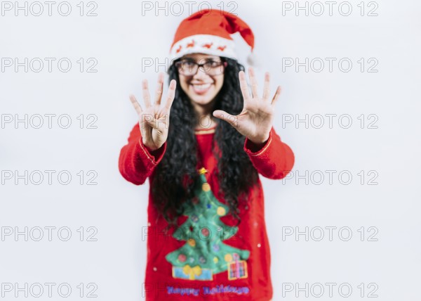 Happy girl in Christmas hat counting number NINE, isolated. Smiling girl in Christmas sweater