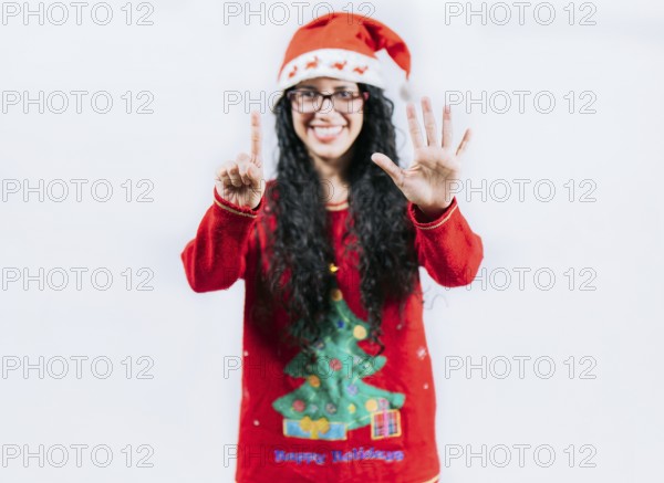 Happy girl in Christmas hat counting number SIX, isolated. Smiling girl in Christmas sweater