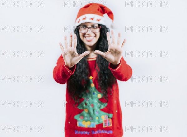 Happy girl in Christmas hat counting number TEN, isolated. Smiling girl in Christmas sweater