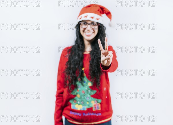 Happy girl in Christmas hat counting number two, isolated. Smiling girl in Christmas sweater