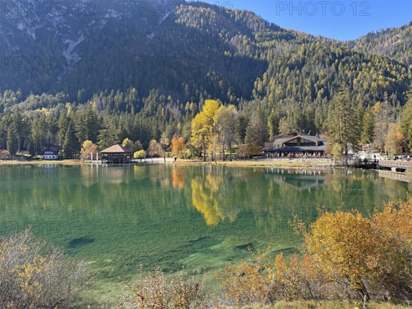 Calm lake with colorful autumn leaves and mountains in the background, Lake Toblach, Lake Dobbiaco,