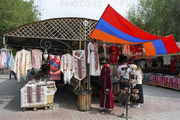 Market stand with traditional clothing and colorful textiles under the Armenian flag, Vernissage