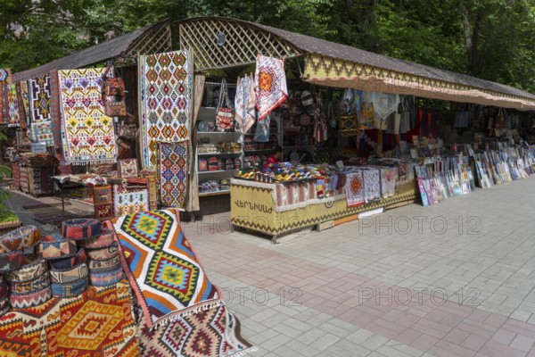 Carpet stand at a market with colorful patterns, cloths and souvenirs in an open setting,