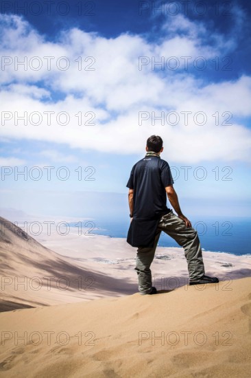 Young man looking at the view from Alto los Verdes, in Atacama Desert. Iquique, Tarapaca Region,