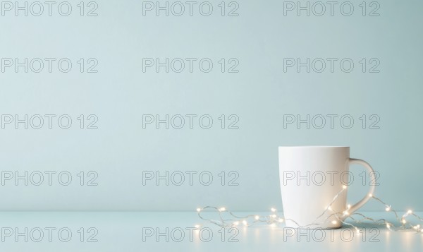 A white coffee cup sits on a table next to a string of lights. The scene is simple and calming,
