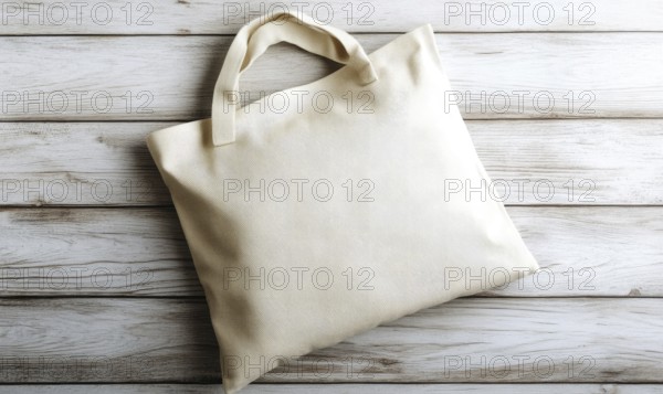 A white bag with a handle sits on a wooden surface. The bag is empty and has a simple design.
