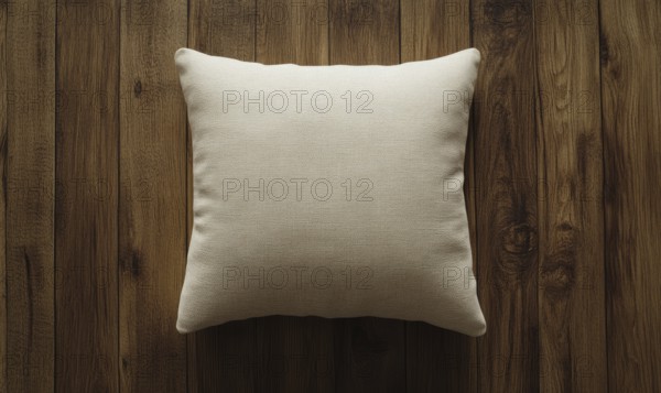 A white pillow sits on a wooden surface. The pillow is unmade and has a simple design. The wooden
