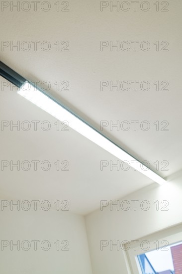 Slim LED light strip on white ceiling next to a window, clear and modern, house renovation, energy