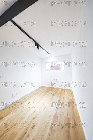 Narrow room with oak flooring and window, the black light track accentuates the clear design, house