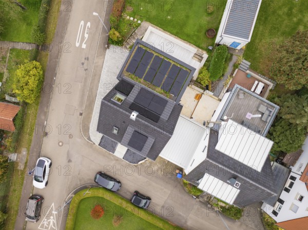 Aerial view of a residential building with PV system and neighboring buildings, well-kept gardens