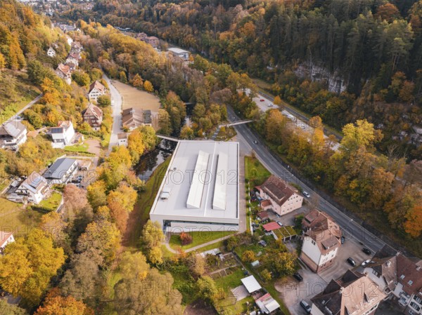 Sports hall located in an autumn landscape with surrounding forest and nearby roads, Walter Lindner