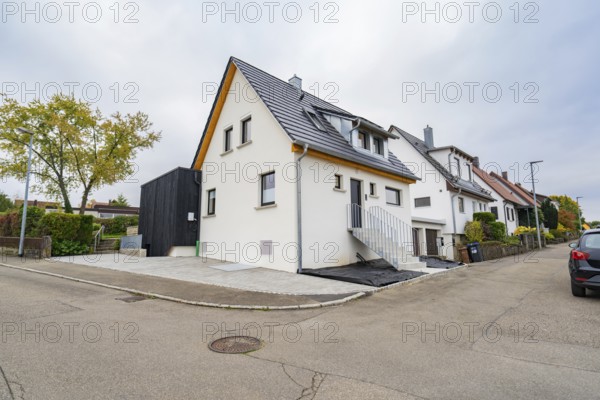 Modernized residential building on a quiet street corner with bright façade under cloudy sky, house