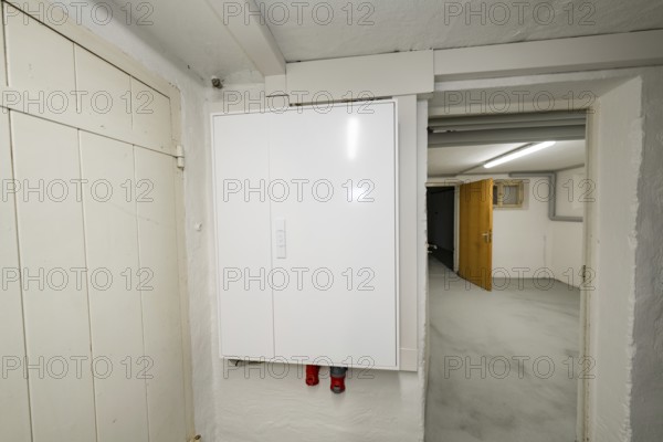 Simple basement corridor with white electrical distributor on plastered wall, objectively