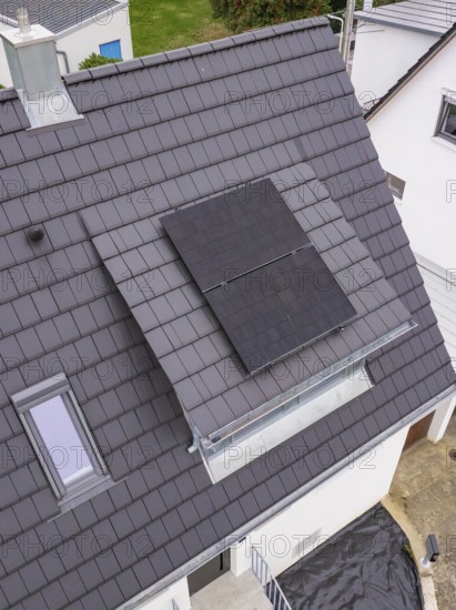 Detail of the roof opening with glass balustrade and two solar modules next to a skylight on a