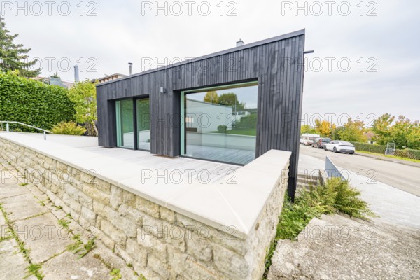 Contemporary extension with large glass front and terrace over a natural stone wall, house