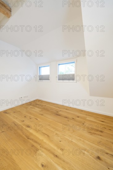 Cosy attic room with warm oak floor and two low windows, house renovation, air conditioning