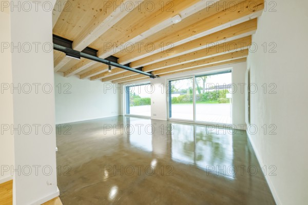 Large, bright living room with exposed wooden beams, polished concrete floor and large sliding