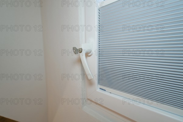 Detail of a lockable white window handle with integrated blind, house renovation, climate
