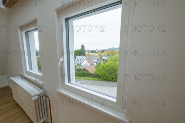 Bright room with white windows and views of residential buildings and greenery, radiator on the