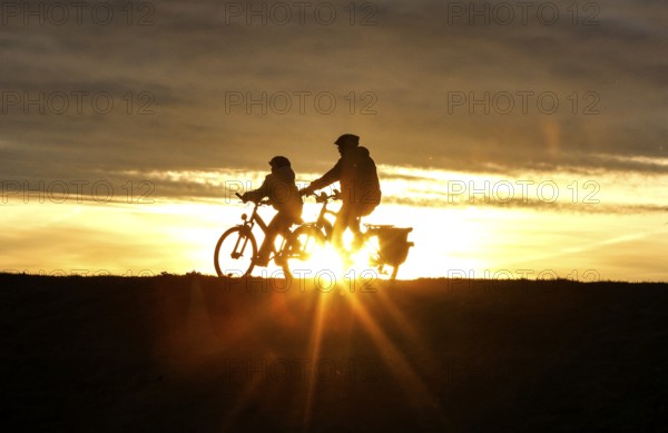 Cyclists ride on a cycle path on the island of Fehmarn at sunset, 13.10.2025, Fehmarn,