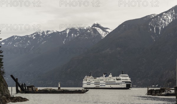 A ferry sails through calm waters with snow-capped mountains in the background in Horseshoe Bay,
