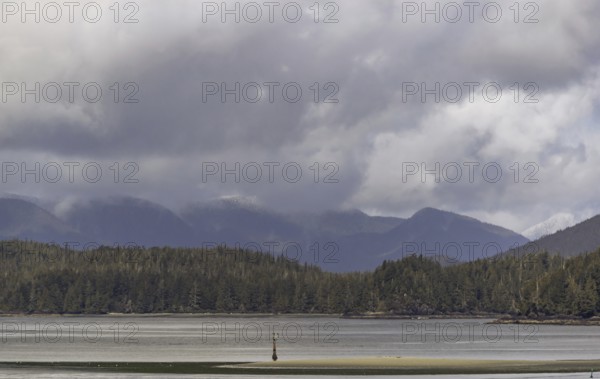 A peaceful lake with surrounding hills creating a tranquil natural scene under an overcast sky in