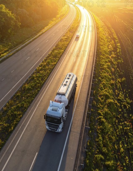 Petrol cargo truck lorry tanker driving on highway hauling oil products at sunrise, wide hilly
