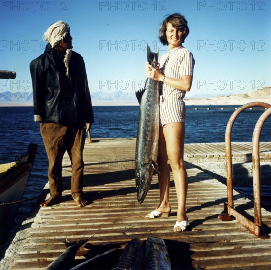 Woman and Egyptian with large captive barracuda, large barracuda (Sphyraena barracuda), about 1, 40