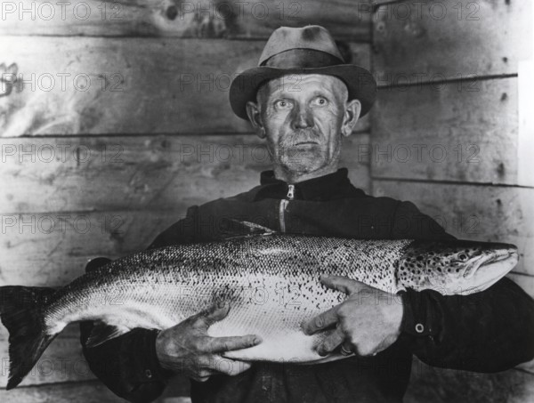 Fisherman with large salmon, presumably a king salmon or quinnat (Oncorhynchus tshawytscha), ca.