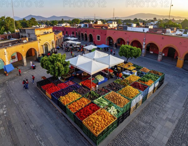 Traditional Mexican plaza with crates of peppers, onions, and tomatoes, economic prosperity in