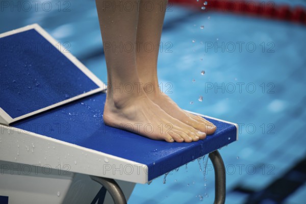 Feet of a woman on a starting block in a swimming pool. Preparation for competition and athletic