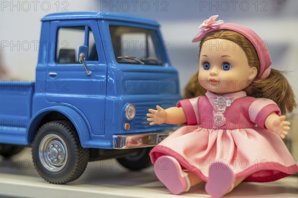 Cute doll in pink dress and blue toy car. Gender stereotypes in children's toys and color coding
