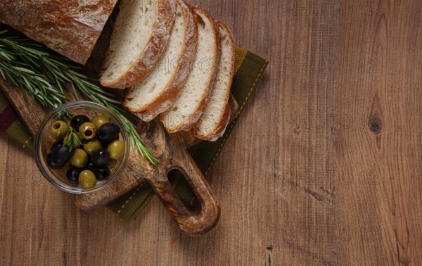 Sliced ciabatta, on a chopping board, with rosemary and olives, Italian bread, close-up, Italian