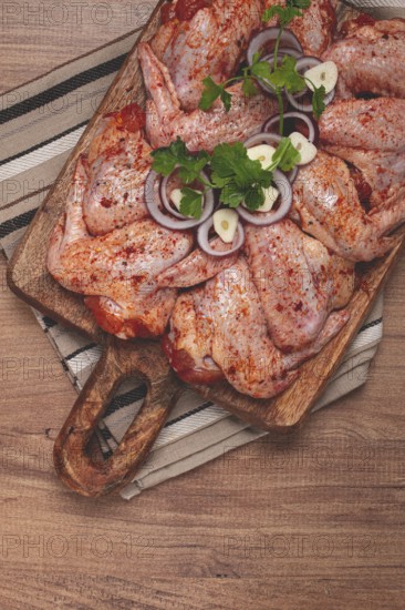 Chicken wings, marinated and laid out on a wooden platter, ready for cooking, grilling or baking,