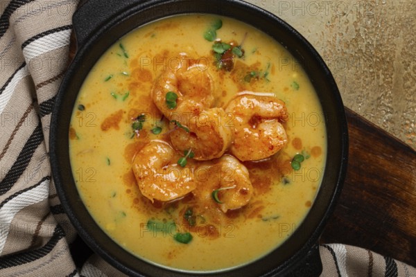 Creamy shrimp curry with spices, garnished with herbs, on a textured background, homemade, no