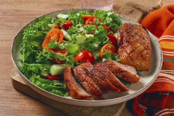 Delicious grilled duck breast served with fresh garden salad and cherry tomatoes at a rustic dining