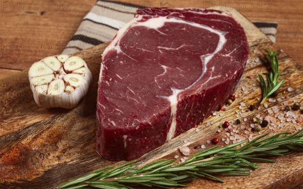 Raw steak, beef steak, rib eye steak, on a cutting board, freshly frozen, with spices and herbs, on