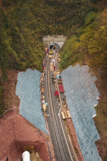 Rail construction in the forest with tunnel opening, surrounded by autumn leaves,