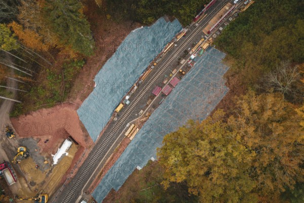 Railway line from above, surrounded by autumn colors, with construction work on the tracks,