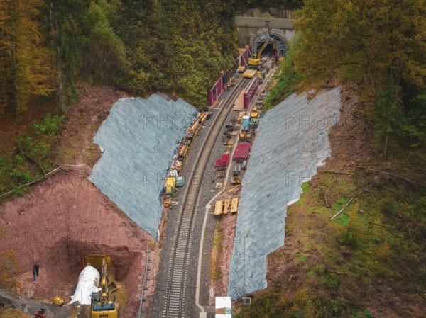 Working at the tunnel entrance to a railway line, with construction equipment and soil in an autumn
