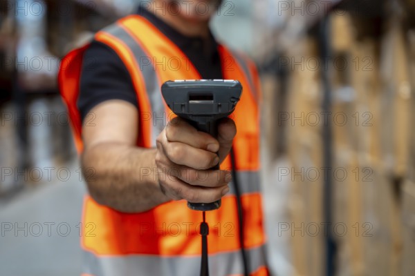 Warehouse worker wearing a safety vest using a barcode scanner to manage inventory and streamline