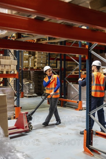 Diverse team of warehouse workers communicating while managing inventory and moving goods with a