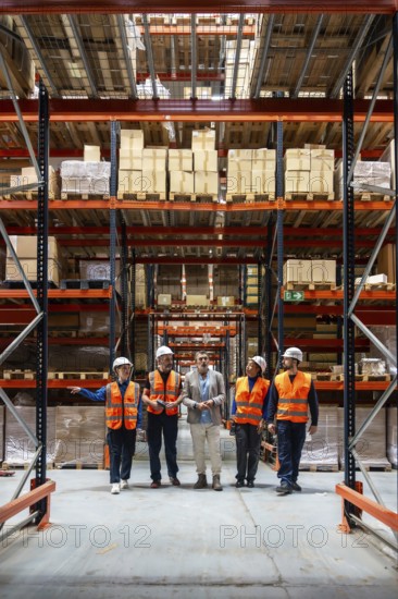 Diverse group of logistics professionals and warehouse workers discussing inventory management and