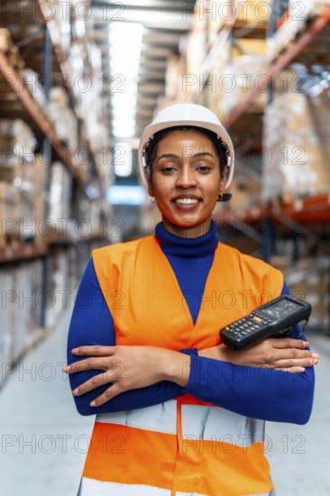 African american woman worker wearing a safety vest and hard hat, holding a portable scanner,