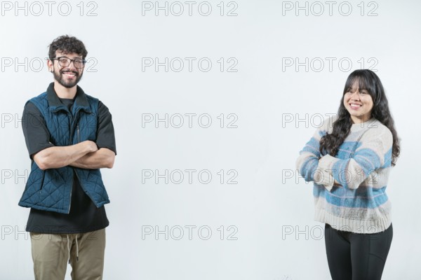 Cheerful young multiethnic couple with arms crossed, isolated. Smiling young couple with crossed