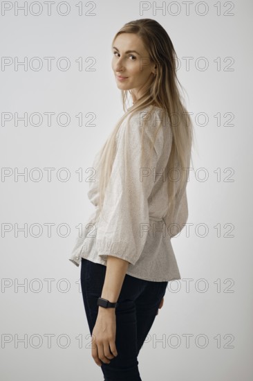 A woman turns back showcasing her long hair and stylish outfit. She gazes over her shoulder,