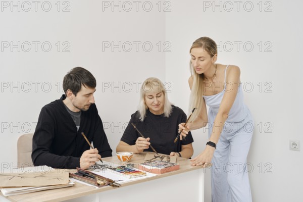 Three artists are engaged in a creative painting workshop. They share techniques and ideas while